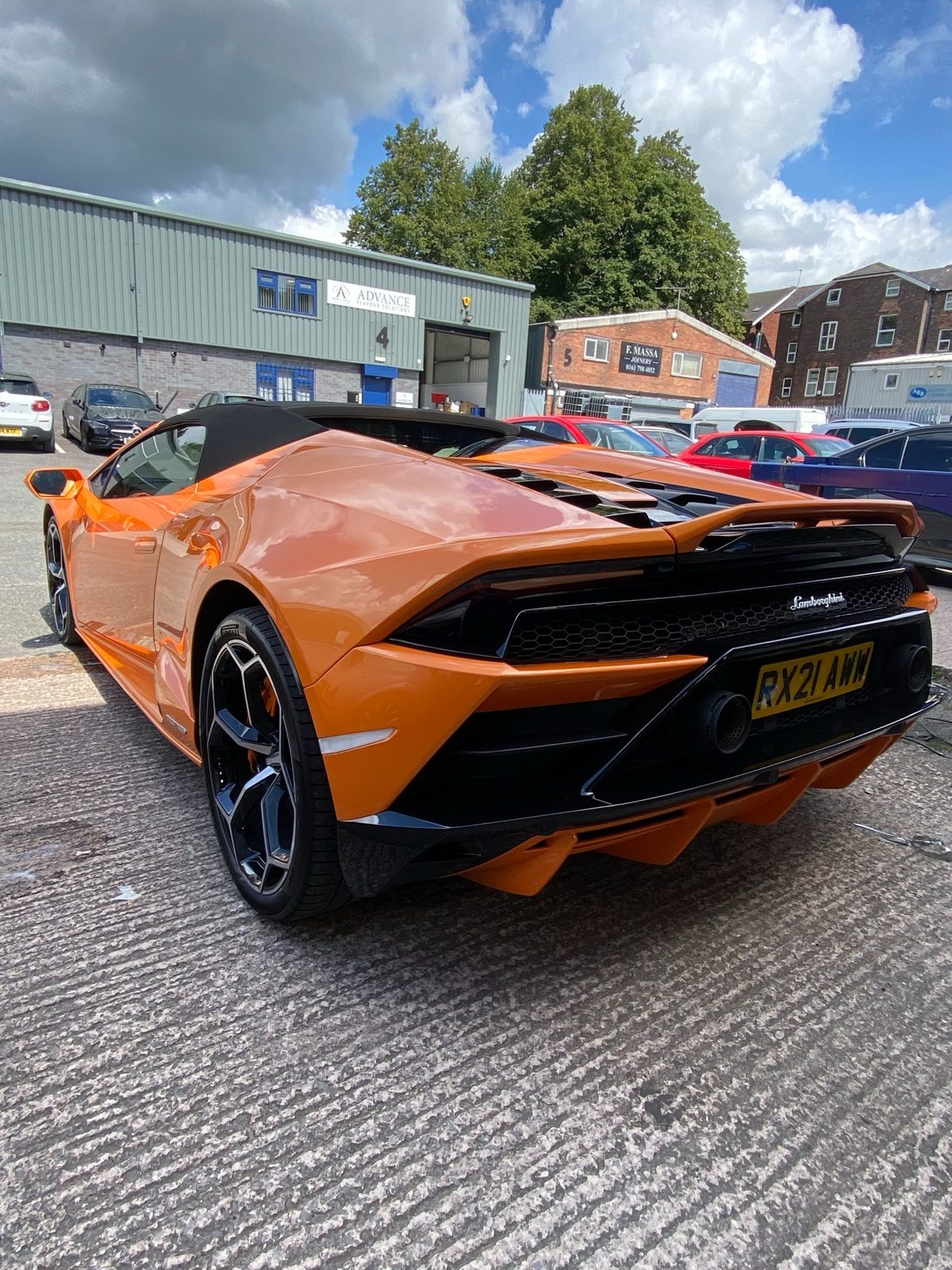 Orange Lamborghini photographed from the front outside a workshop